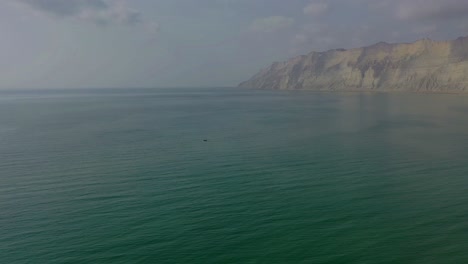 Aerial-Over-Arabian-Sea-With-Rugged-Mountains-Of-Hingol-National-Park-In-Background