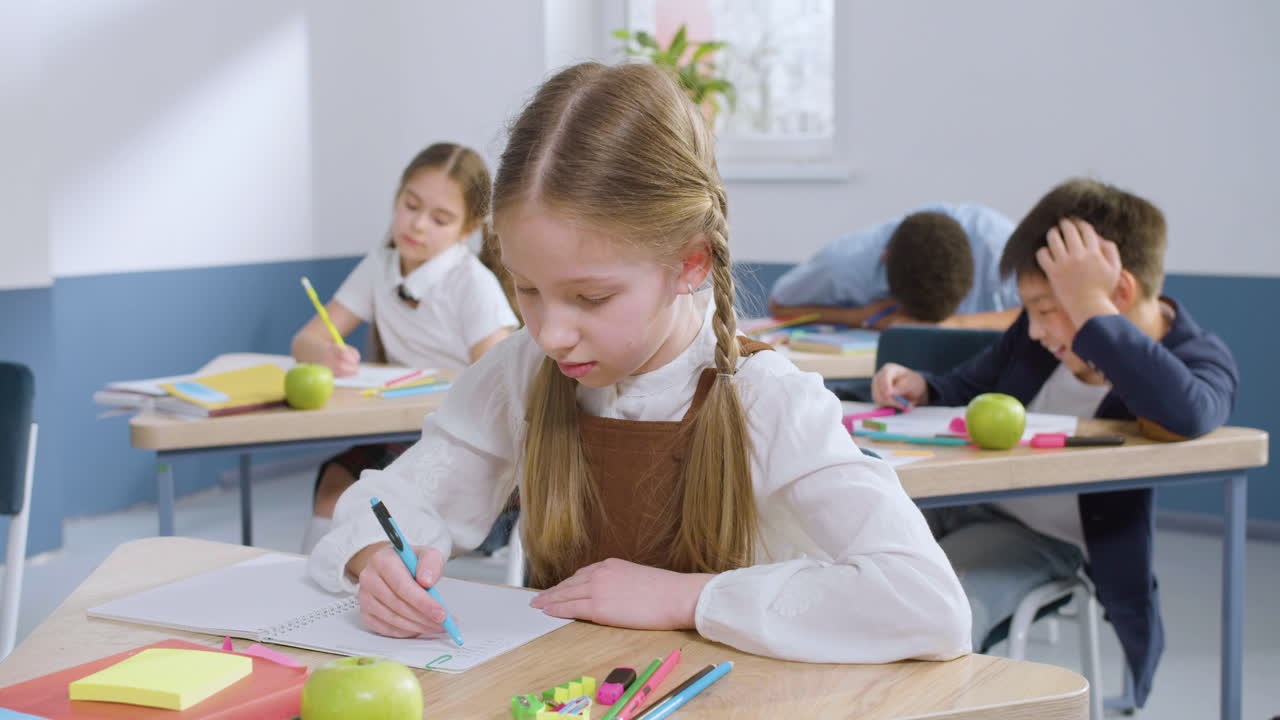 Close Up View Of Female Student Sitting At Desk In English Classroom Writting In Her Notebook