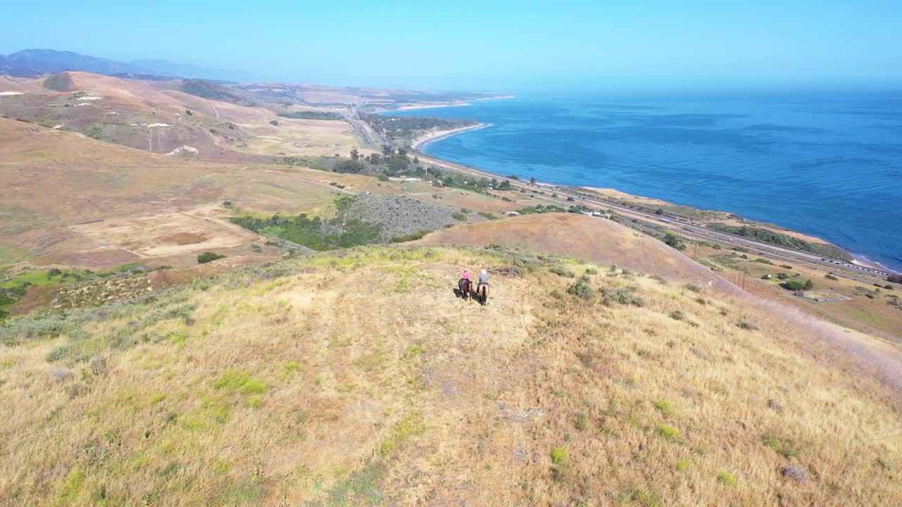hermosa antena de una pareja de jubilados montando caballos a caballo en un rancho con vista al océano pacífico en santa barbara california 4