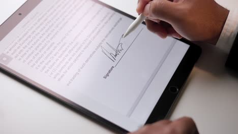 close up businessman hand working electronic signature on tablet by stylus at night. write business agreement of contract. man signing contract on tablet. business and technology concept.