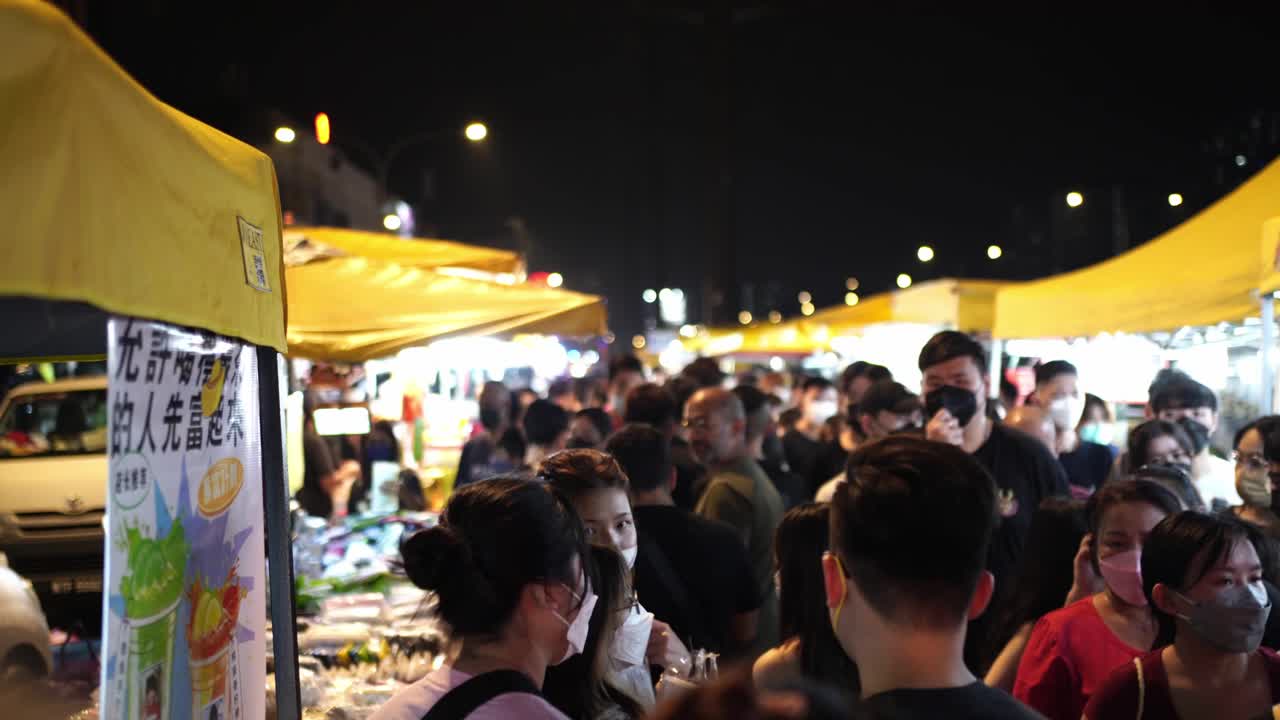 A lively scene of a vendor table showcasing Malaysian delicacies in Kuala Lumpur, with customers examining the offerings and a vibrant sign highlighting refreshing fruity drinks.