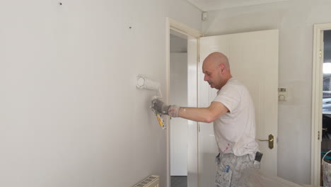 a skilled decorator paints a wall with a roller in a contemporary living room creating a clean and updated look.