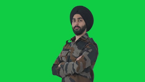 retrato de un sikh confiado hombre del ejército indio de pie con las manos cruzadas pantalla verde