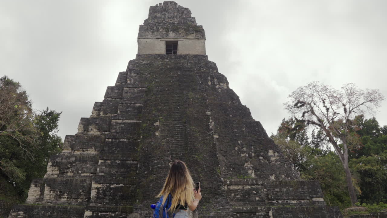 Tourist woman turn to watch Tikal Pyramid temple I Guatemala. Solo traveler. Independent Slow motion