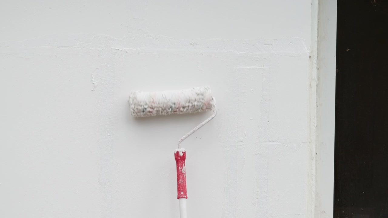 Rullo da imbianchino che stende pittura bianca su una parete.