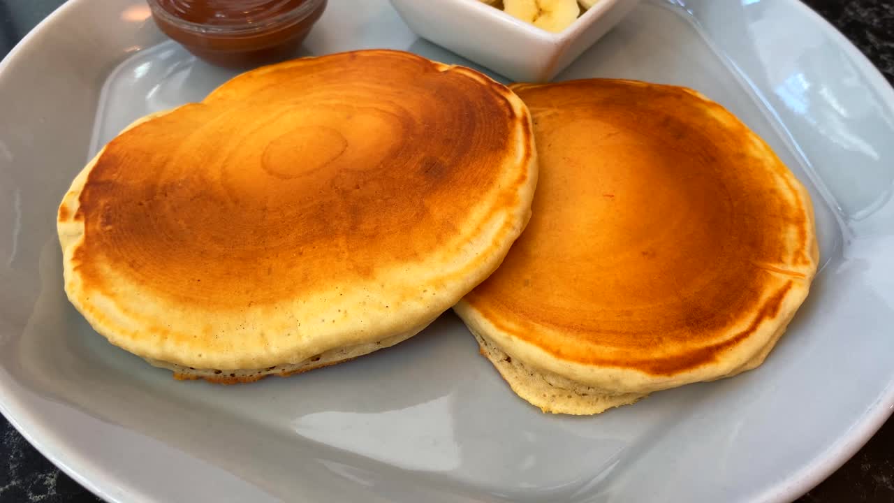 sabrosos panqueques dorados con plátanos y salsa de chocolate al lado, desayuno, tiro de 4k