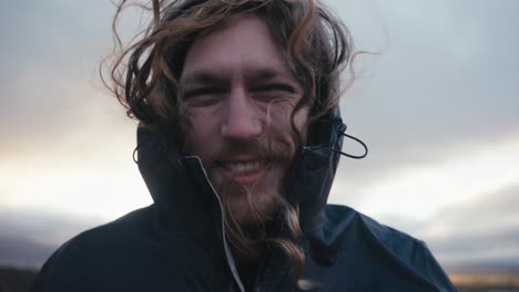 medium close up of a male hiker in the wilderness laughing as his long hair blows in the wind