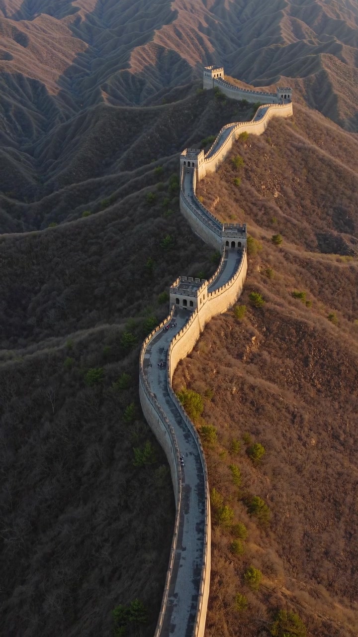 Luftaufnahme der Chinesischen Mauer, die sich bei Sonnenaufgang durch Berge schlängelt.
