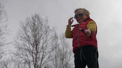 Cool-young-boy-with-sunglasses-and-toy-gun-on-moody-gray-day