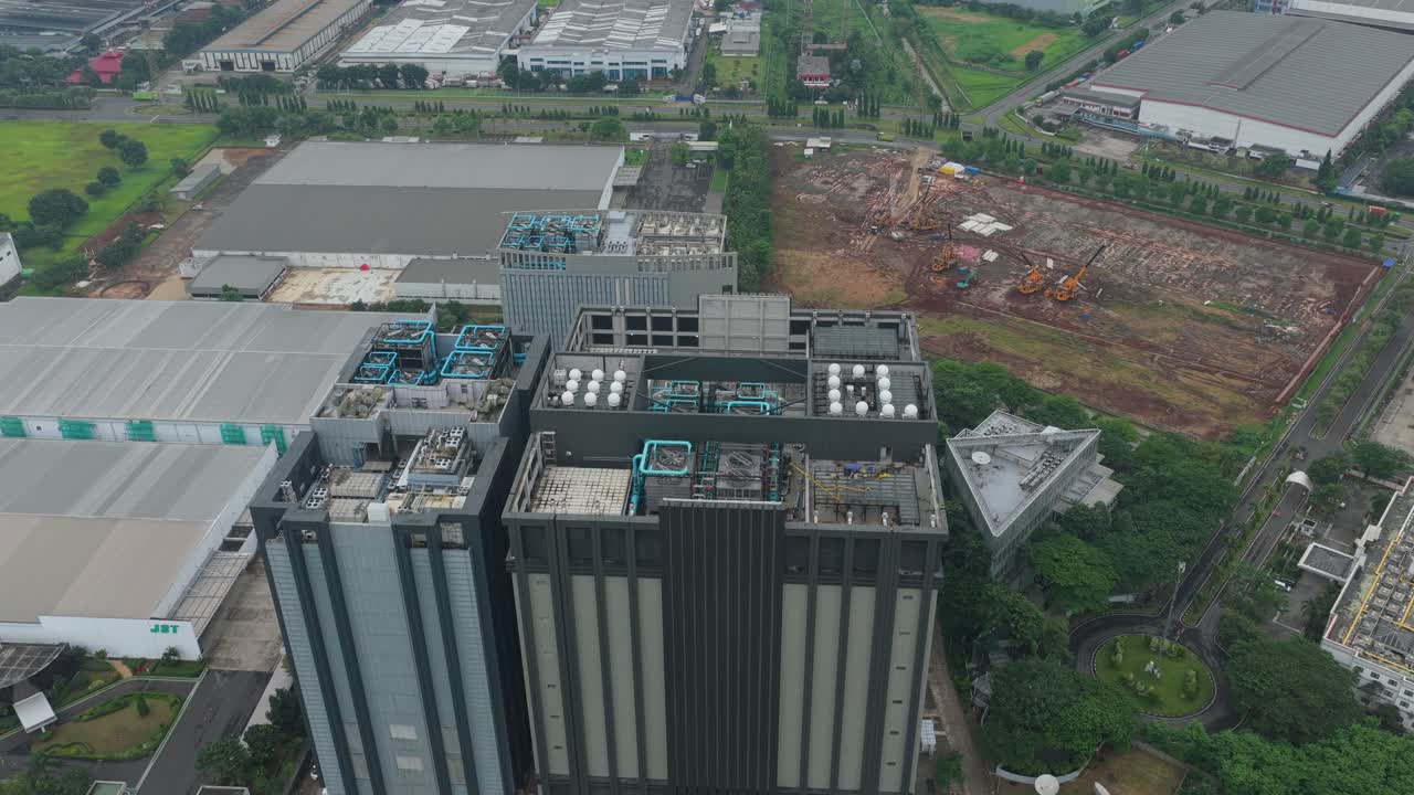 Højtliggende luftfoto, der langsomt cirkler om en stor, moderne datacenterbygning beliggende i et industriområde i Jakarta, Indonesien