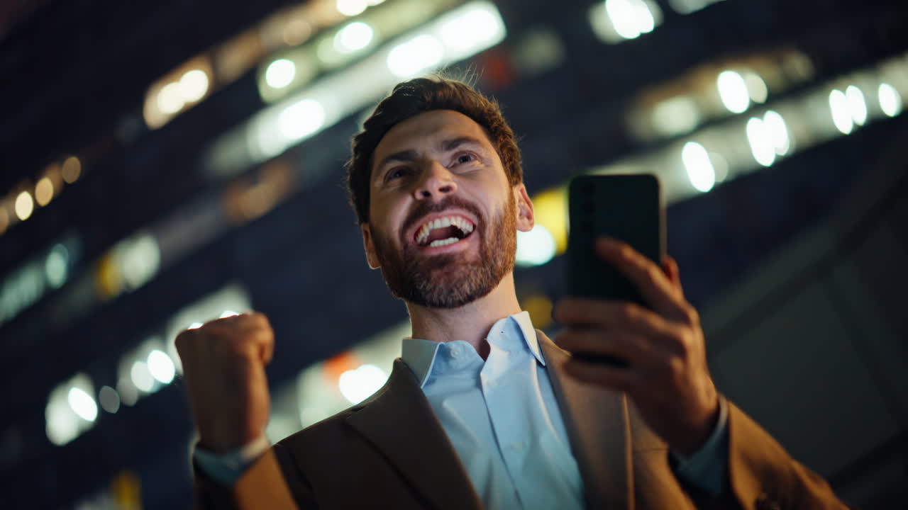 Victorious entrepreneur checking mobile celebrating in night downtown portrait