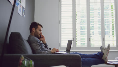 Männliche-Führungskraft-Spricht-Mit-Dem-Mobiltelefon,-Während-Sie-Einen-Laptop-In-Einem-Modernen-Büro-In-4K-Verwendet