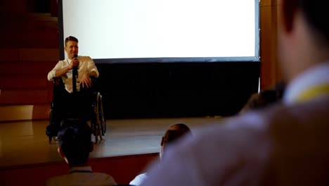 joven hombre de negocios discapacitado caucásico hablando en un seminario de negocios en el auditorio 4k