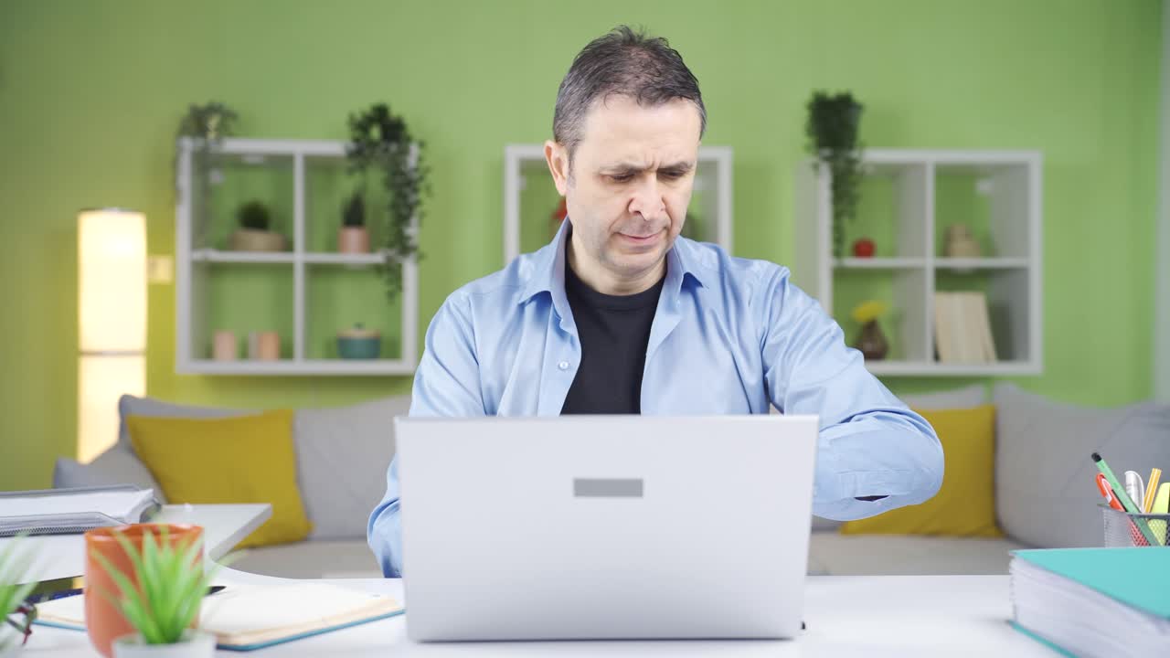 el trabajador de la oficina en casa, que está bajo presión de tiempo, mira constantemente su reloj y trabaja.