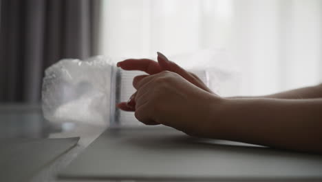 woman kneads fingers nervously sitting at table in kitchen