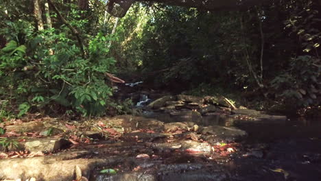 aerial shot flying under a hammock over a small waterfall in the jungle