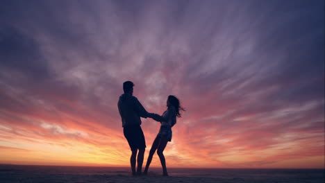 Happy-couple-dancing-on-beach-enjoying-honeymoon-in-nature-at-sunset-silhouetted-wide-shot-RED-DRAGON