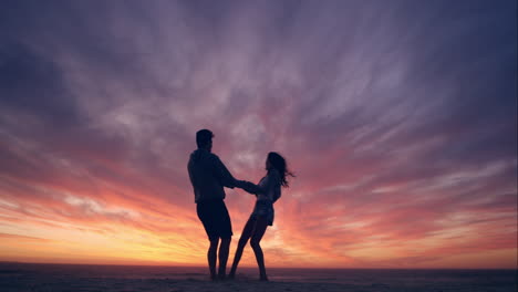 pareja feliz bailando en la playa disfrutando de la luna de miel en la naturaleza al atardecer silueta amplia tiro dragón rojo
