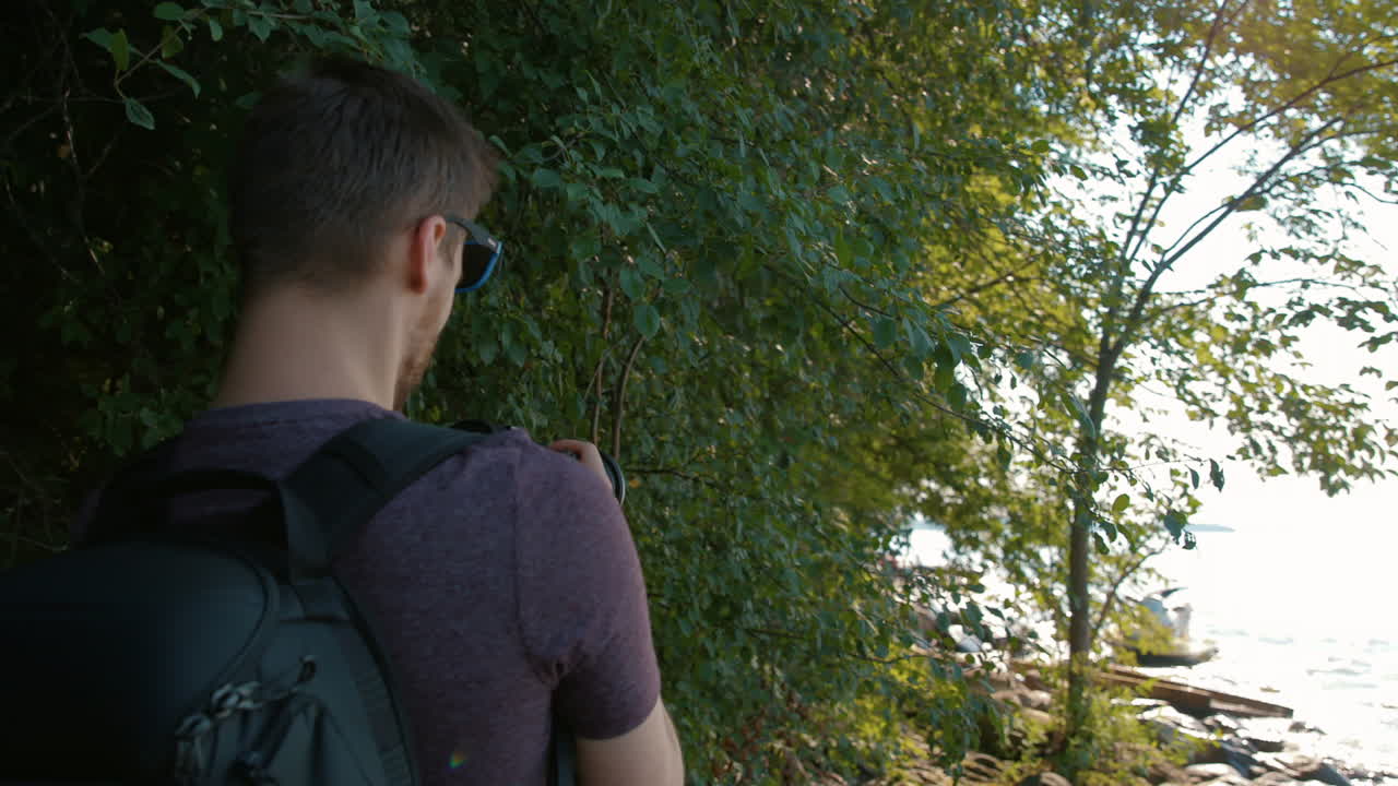 남자는 해변에서 나무에 나뭇잎의 사진을 찍는다