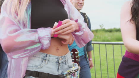 Un-Grupo-De-Jóvenes-Amigos-En-La-Entrada-Del-Festival-De-Música-Poniéndose-Pulseras-De-Seguridad.