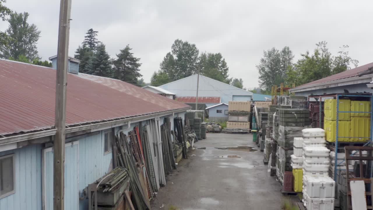 Military storage alley of vintage parts on a rainy wet day aerial through an alley of vintage ww2 building with a gradual rise.
