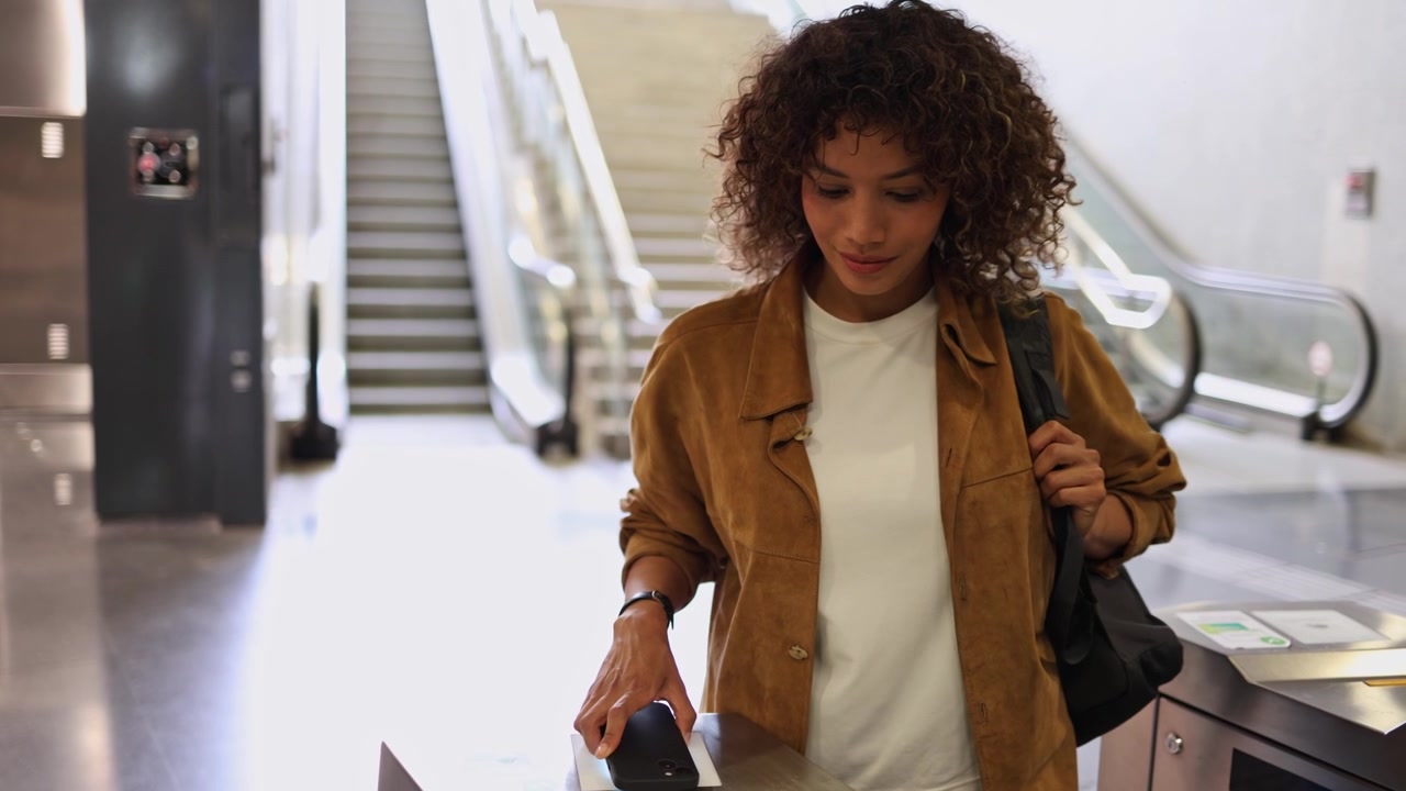 Young Woman Using Smartphone for Contactless Payment at Metro Turnstile