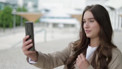 chica caucásica teniendo video chat en el teléfono afuera, gesticulando