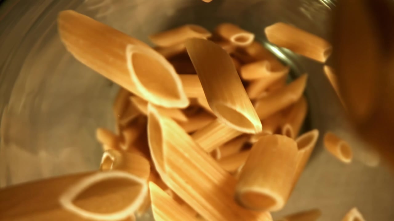 Penne crude che cadono in un contenitore al rallentatore