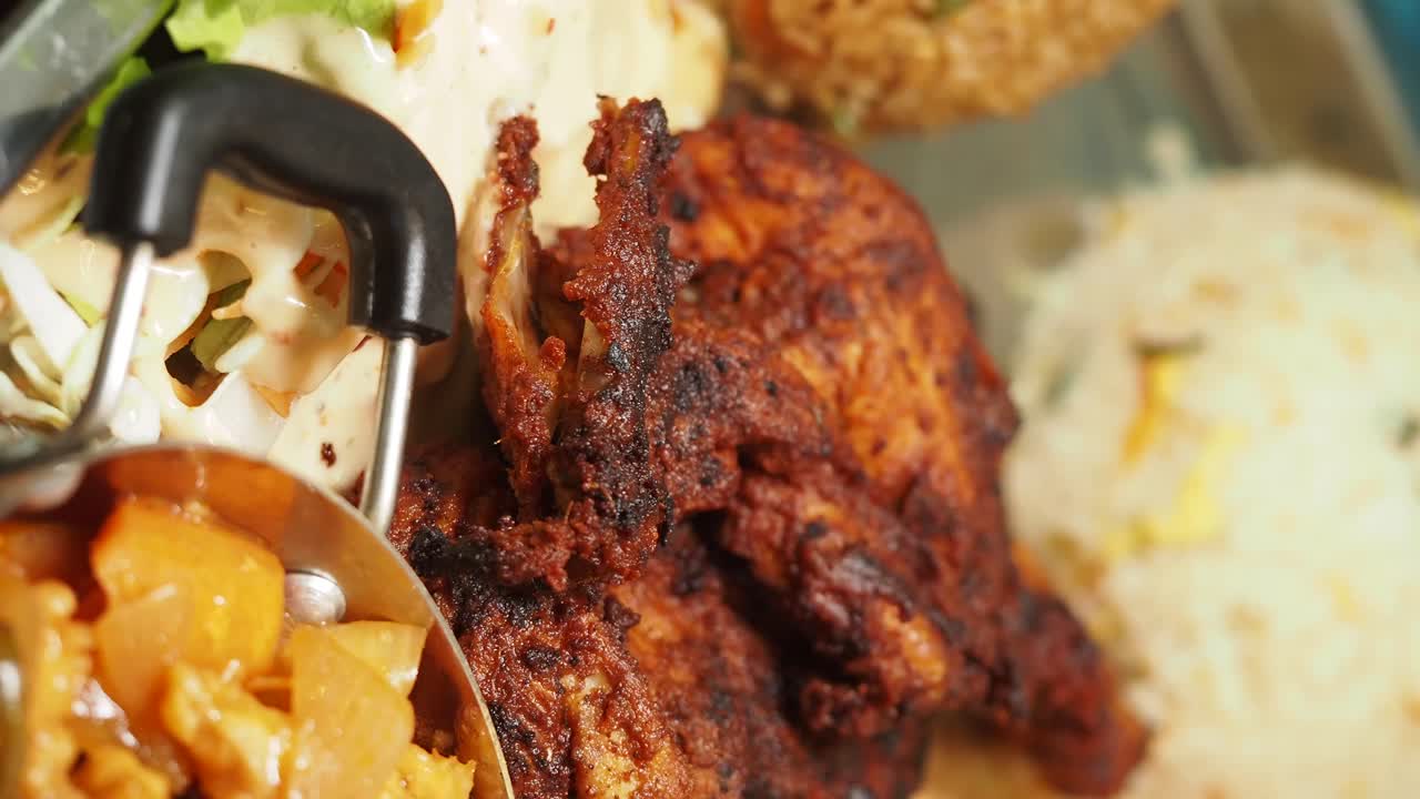 Close-up of roasted chicken served with various side dishes and a hand reaching for the food