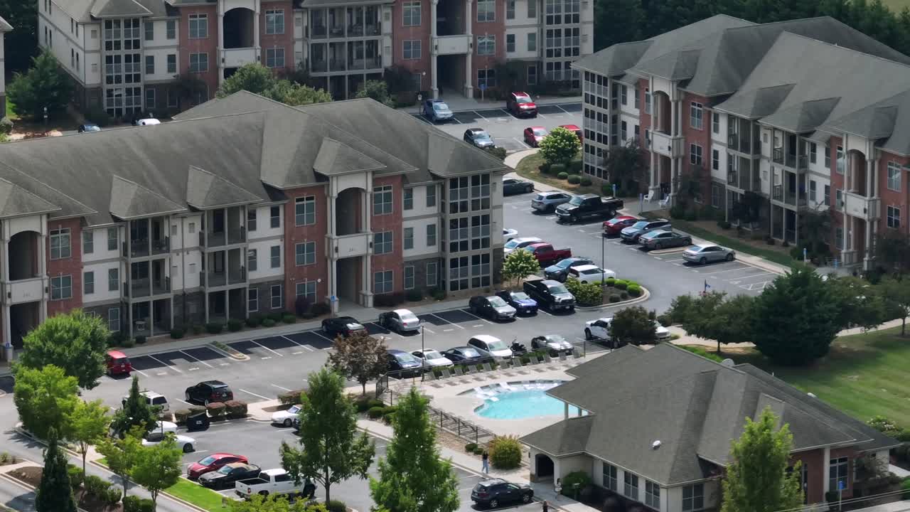 Parking cars in suburb neighborhood with community pool and multi family townhouse apartments. Sunny summer day in noble housing area of USA. Aerial wide shot