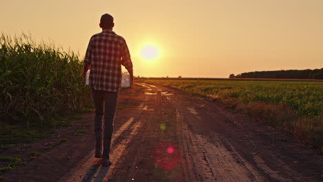 farmer walking down a country road at sunset