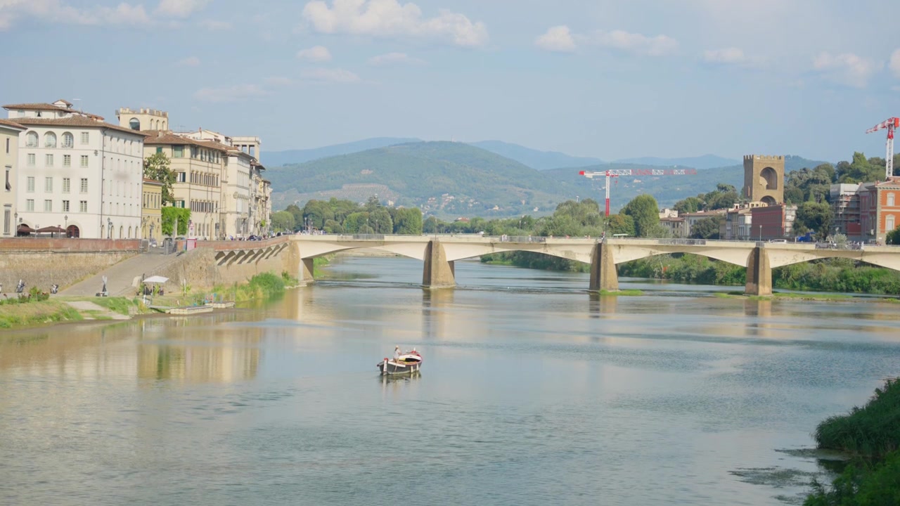 Naturskøn udsigt over Ponte alle Grazie-broen over Arno-floden i Firenze, Italien. Elegant byarkitektur og bølgende toscanske bakker under en lys himmel. Sommerferie, rejseturisme i Europa