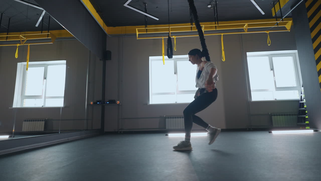 운동 선수 는 체육관 에서 피트니스 클럽 의 서스펜션 운동 을 하기 위해 trx 시스템 을 사용 하고 있다