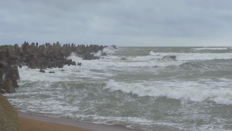 waves breaking against karosta northern pier at liepaja, stormy overcast autumn day, slow motion wide shot