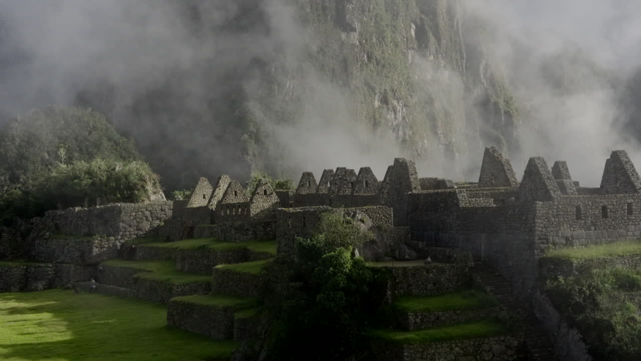 Zoom out of Machu Picchu ruins citadel with Huayna Pichu mountain in background. Wide shot, panorama