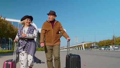 ancianos marido esposa jubilados turistas van a la terminal del aeropuerto para abordar con equipaje sobre ruedas