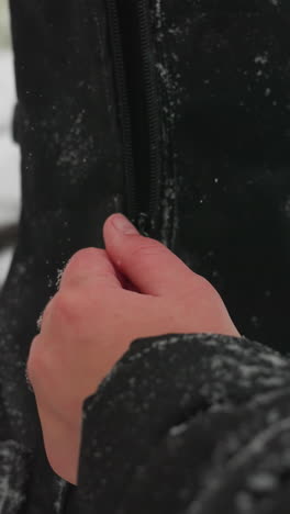 cerca de las manos abriendo el paquete de guitarra al aire libre durante un día de invierno nevado, con suaves copos de nieve cayendo y el fondo natural borroso del parque cubierto de nieve