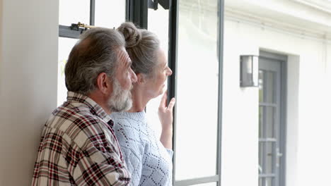 mature couple enjoying peaceful moment together looking out window at home, copy space