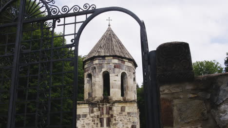 Mtsvane-monastery-church-bell-tower-behind-open-iron-railing-gate