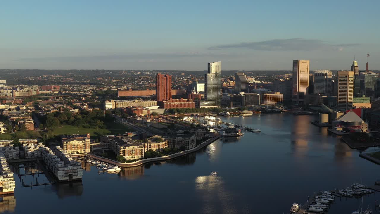 Slow aerial approach of the Inner Harbor of Baltimore Maryland over the Patapsco River at golden hour sunrise