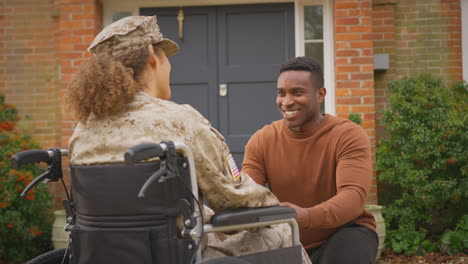 injured female american soldier wearing uniform sitting in wheelchair talking with husband outdoors