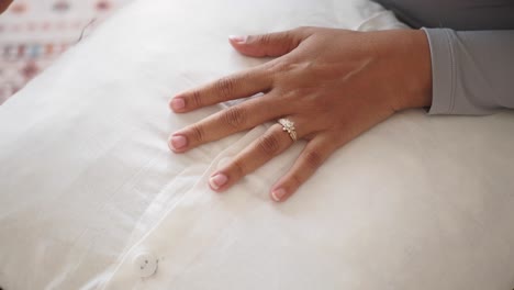 woman's hand with ring on a white pillow