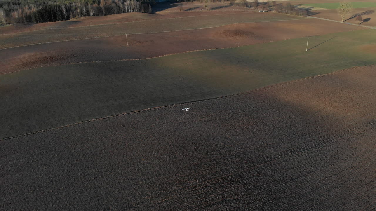 갈색 들판 위를 날고 있는 흰색 무선 조종기