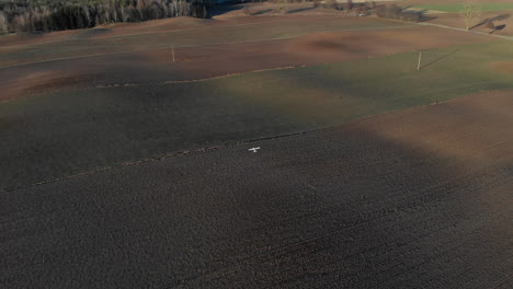 White-radio-control-plane-flying-over-brown-fields