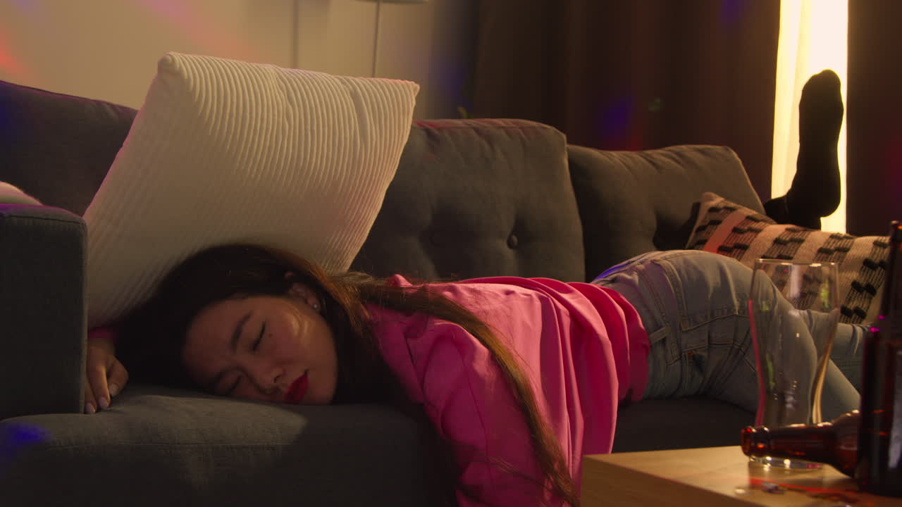 부부는 집 파티에서 술을 마신 후 소파에 쓰러져 숙취로 고통 받고 있습니다.