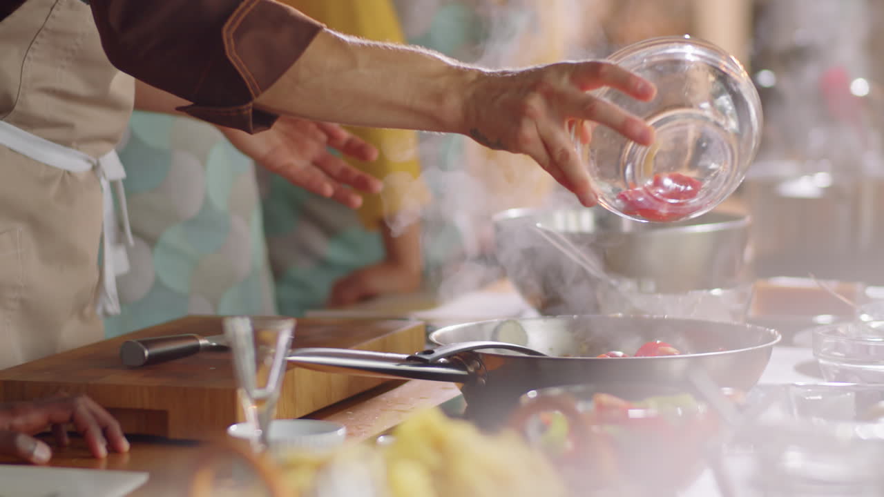 chef poniendo tomates en la sartén durante la clase de cocina
