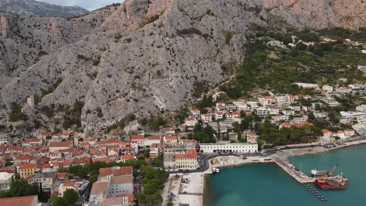 Domy na úpatí drsného pohoří Dinara u města Omiš v Chorvatsku a pobřeží Velika Plaža Punta