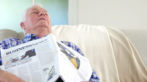 un anciano durmiendo con un periódico encima.