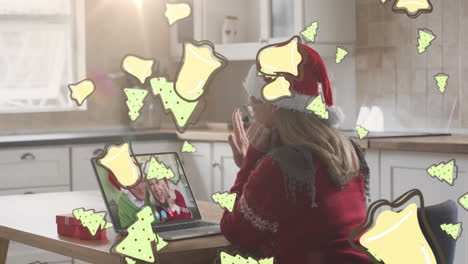 animación de galletas de navidad sobre mujer caucásica en sombrero de santa en llamada de video portátil con la familia