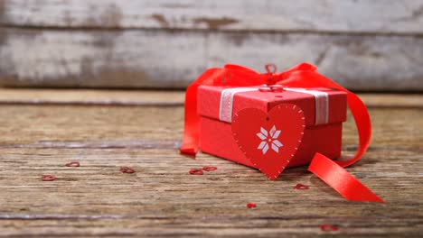 Red-heart-and-gift-box-on-wooden-surface-4k